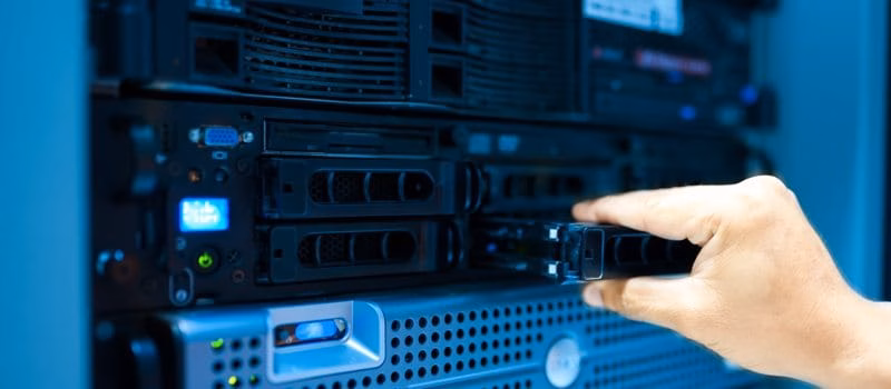 Hand eines IT-Technikers, der eine Festplatte in einen Server im Rechenzentrum einsetzt oder herausnimmt.